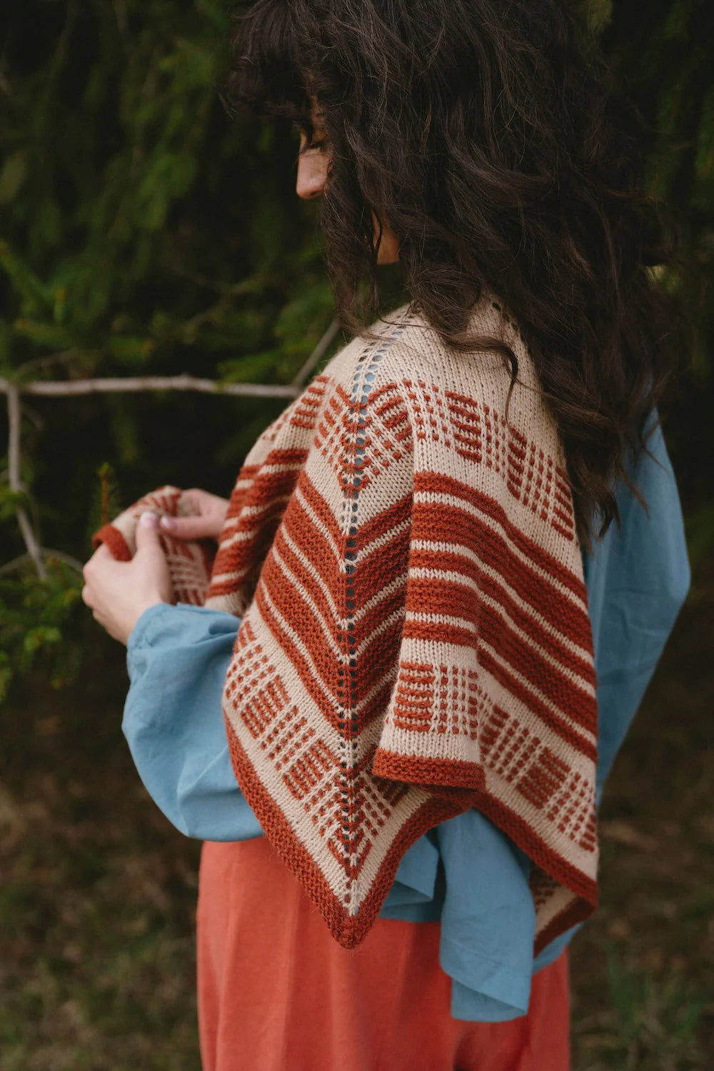 Person with a white and red knit shawl draped over their shoulder.