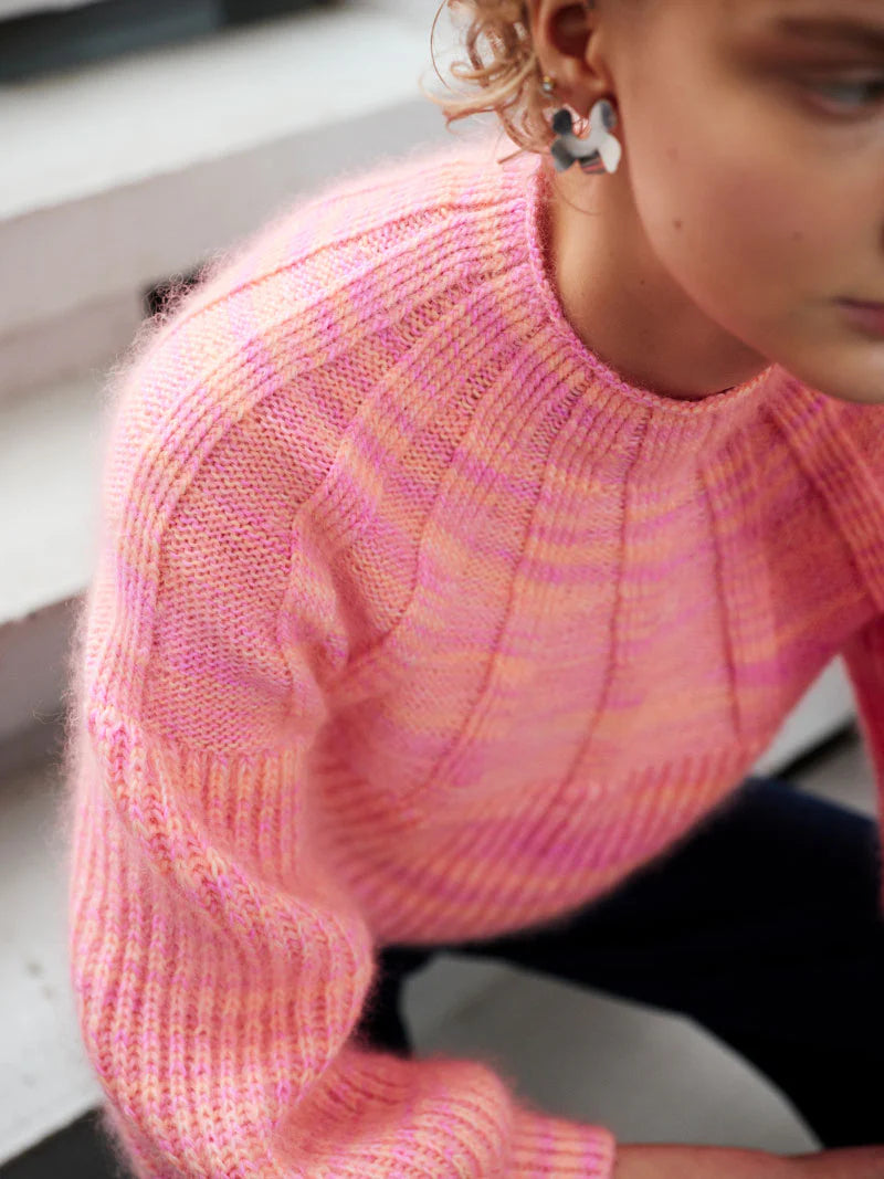 Close-up of a person wearing a pink and orange textured knit sweater.