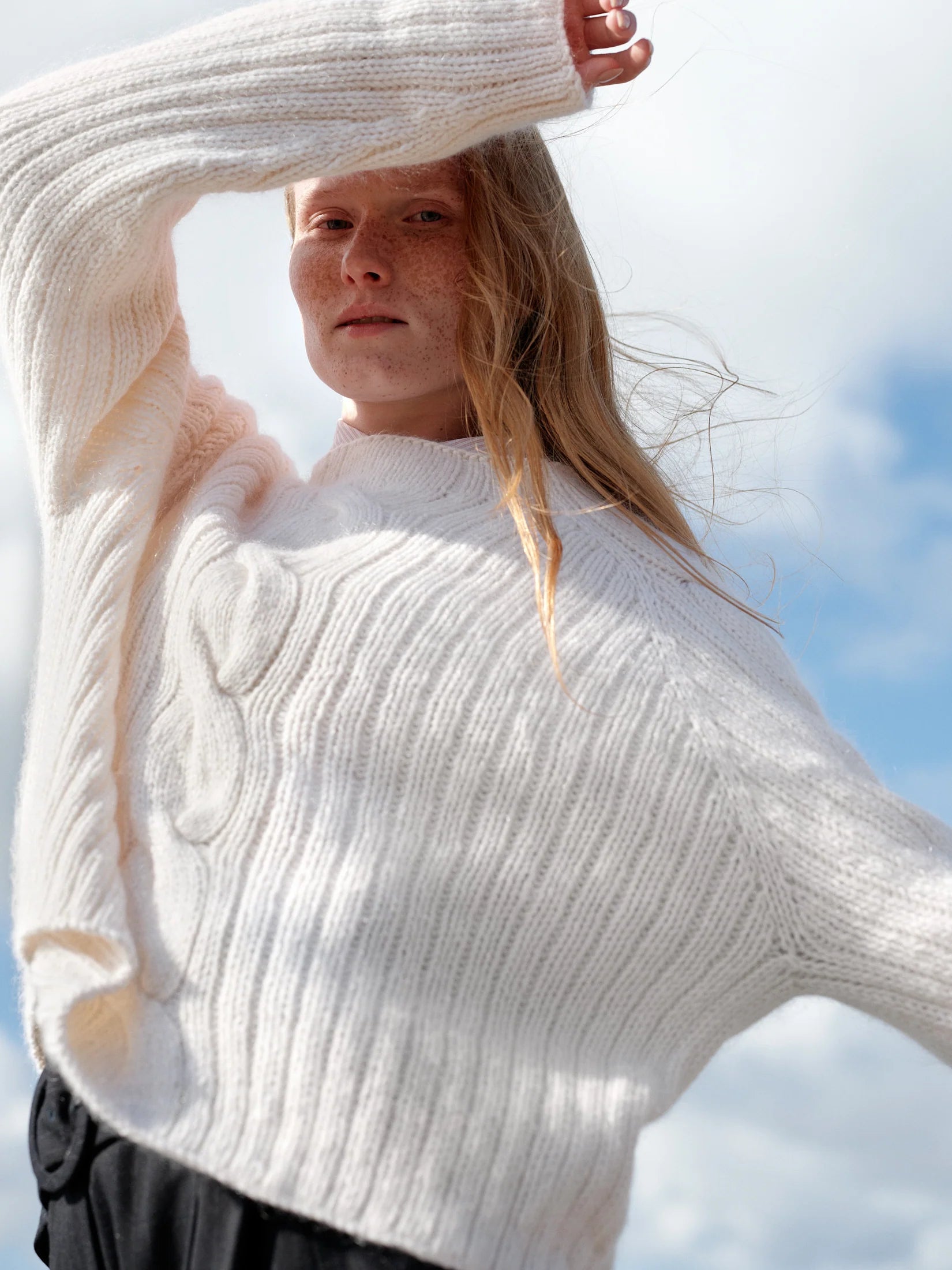 A person wearing a white knit sweater.