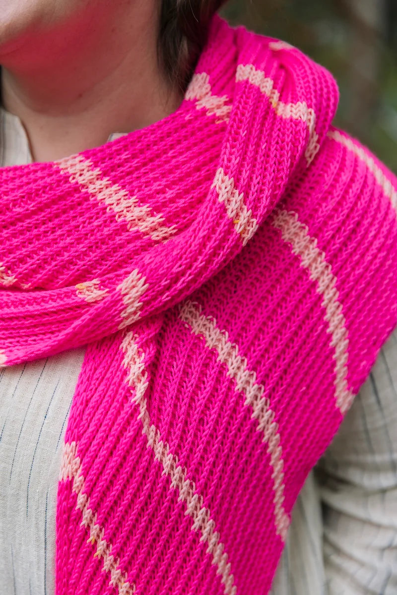 Close-up of a person with a bright pink striped knit shawl wrapped around their neck.